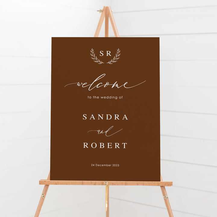 Wedding welcome sign board with calligraphy font and monogram of bride and grooms initials in deep harvest and white ink. Peach Perfect.