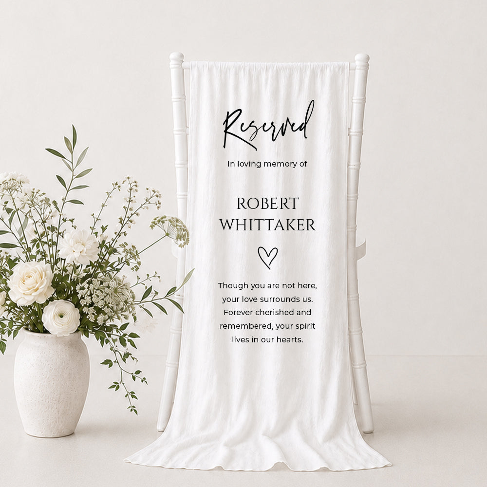 Wedding fabric memorial sign printed on white linen with Reserved in Loving Memory and soft poem hanging over a white ceremony chair.