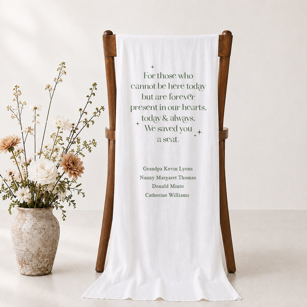 Wedding linen or satin white fabric memorial sign placed over a timber rustic chair with We Saved You A Seat and names of those not present.