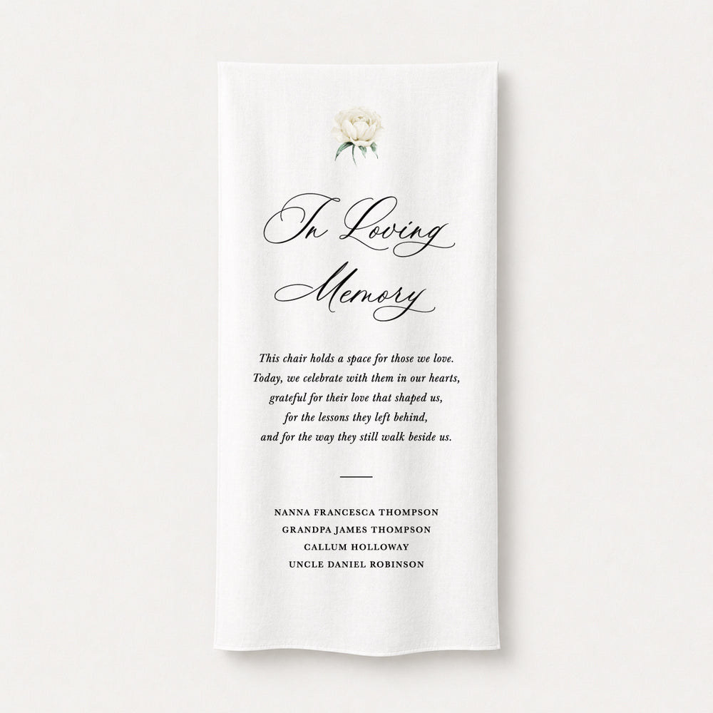 A white fabric memorial linen banner featuring elegant black script text reading 'In Loving Memory' with a small white rose illustration at the top and a poem below.