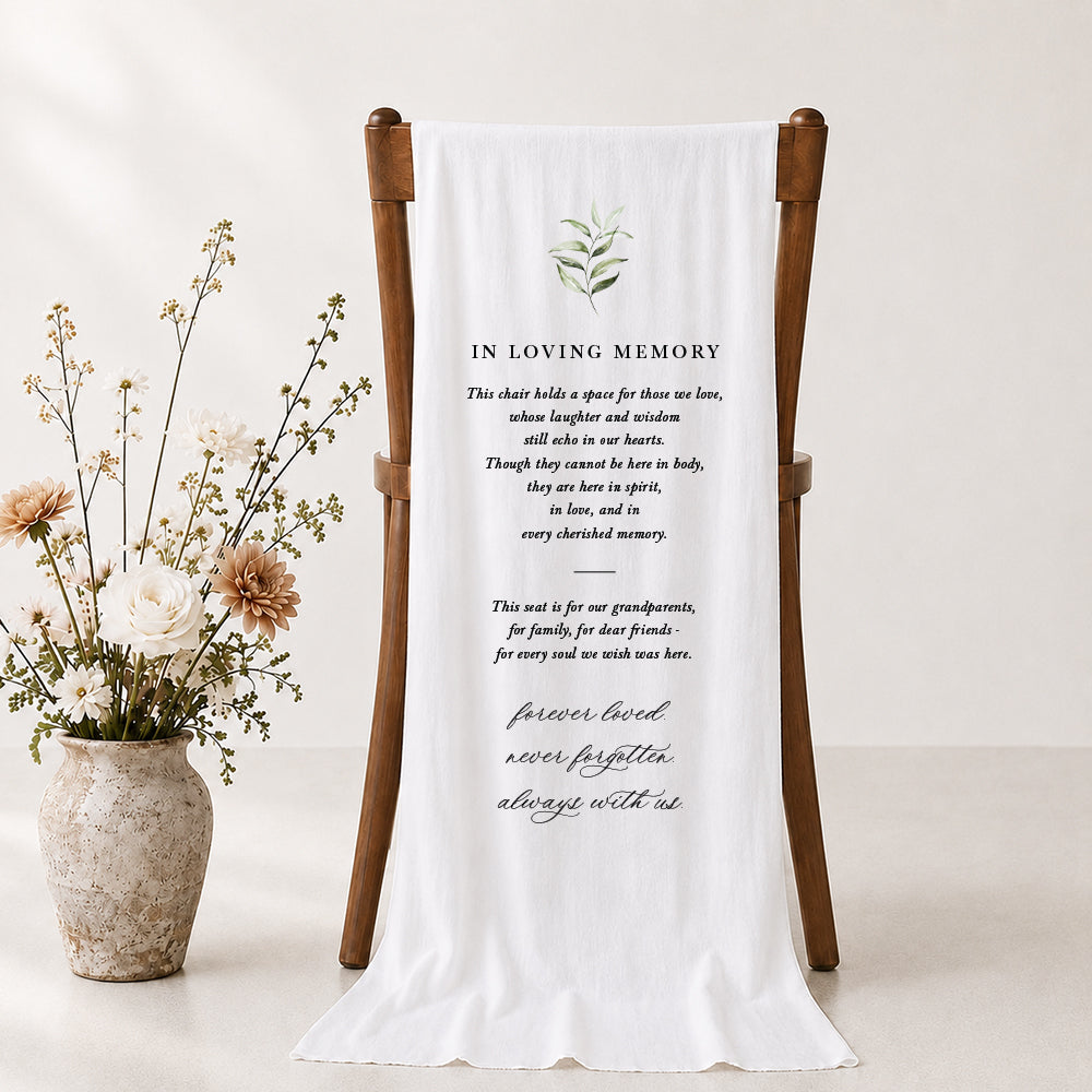 Beautiful wedding memorial sign draping over a timber chair with green leaves and In Loving Memory for the heading.