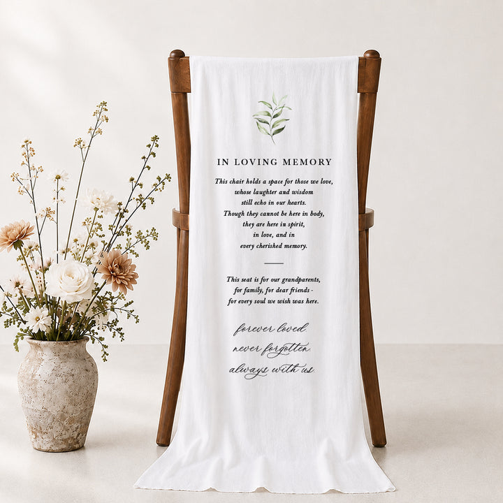 Beautiful wedding memorial sign draping over a timber chair with green leaves and In Loving Memory for the heading.