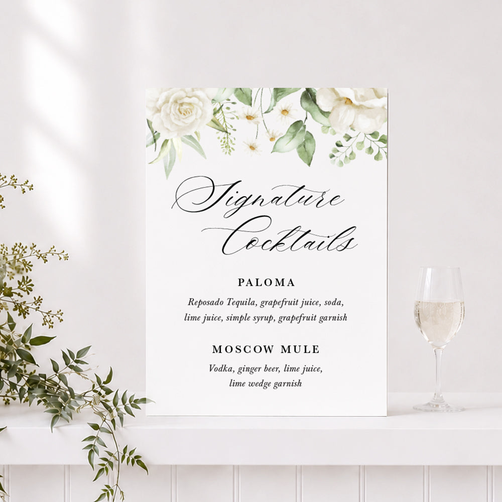 Wedding bar or drinks sign printed on acrylic or foamboard with white flowers and greenery and "Signature Cocktails" heading.