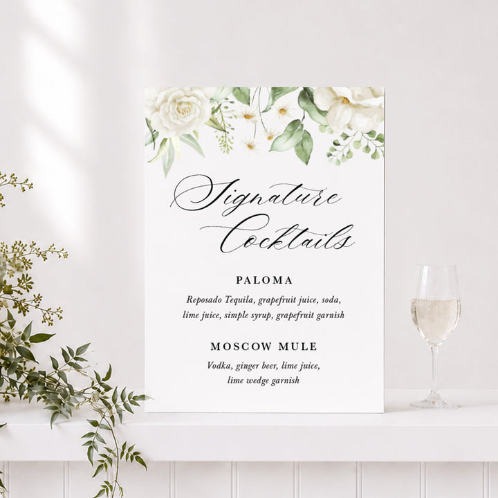 Wedding bar or drinks sign printed on acrylic or foamboard with white flowers and greenery and "Signature Cocktails" heading.