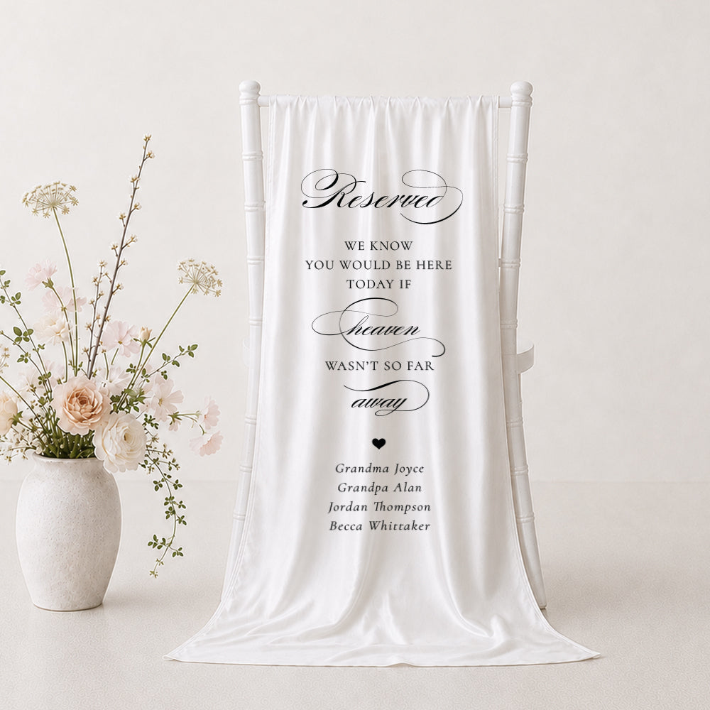 A white fabric memorial banner draped over a white wedding chair, printed with elegant black script and serif text in Australia honouring loved ones.