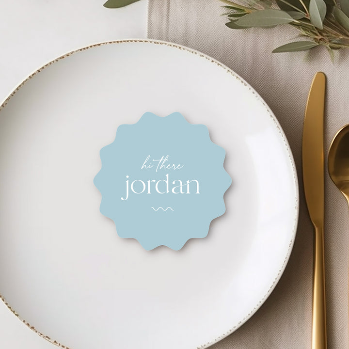 Modern minimalist wavy round blue place card with white text and wavy line. Hi there guest name.