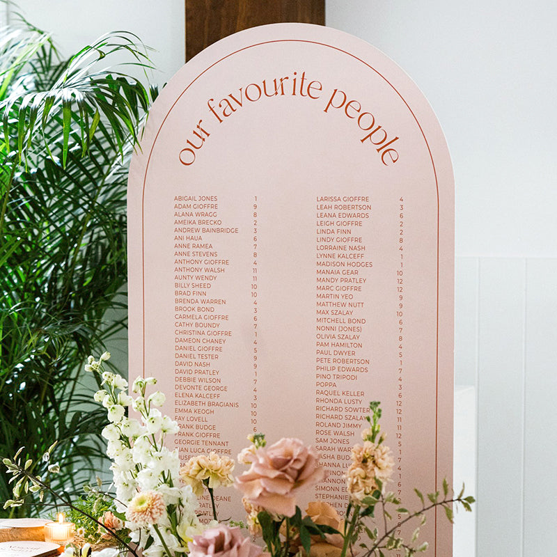 Personalised arched wedding seating chart from the Abigail Collection styled with fresh florals.