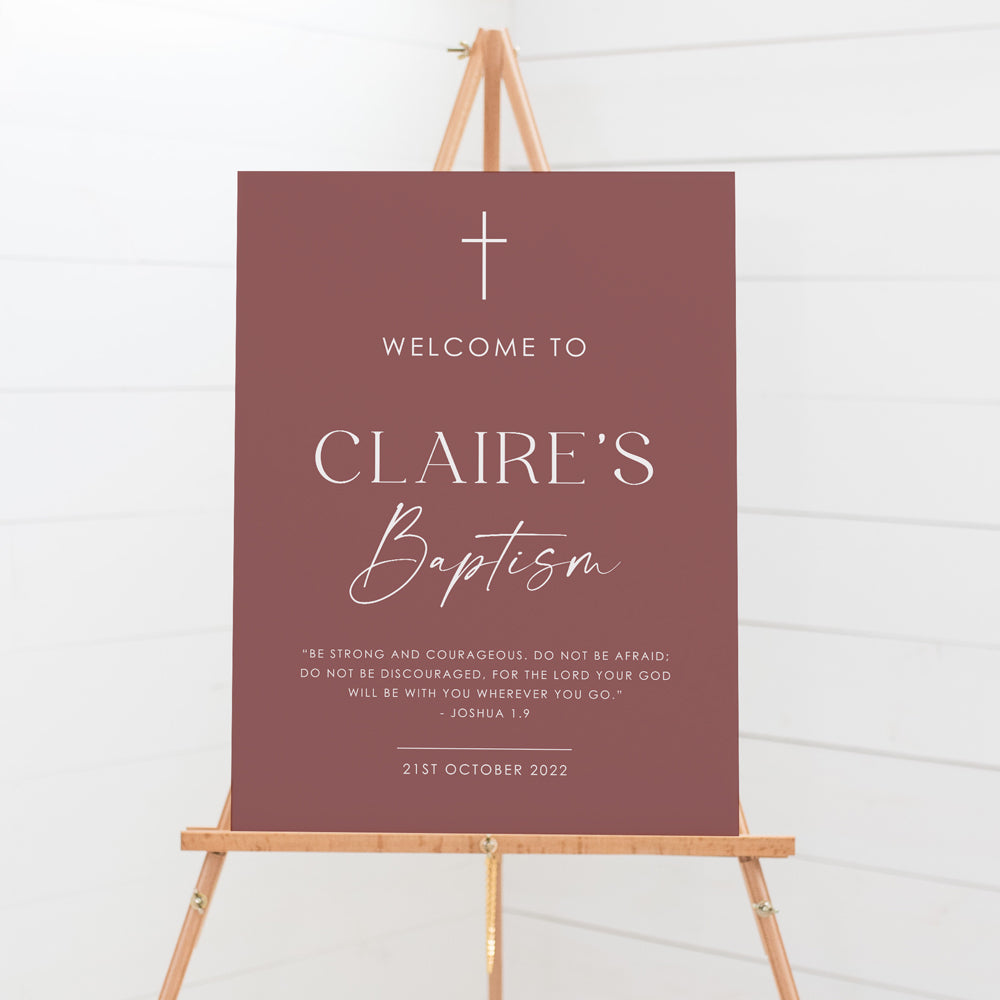 A baptism welcome sign with a dusty rose background and white text, displayed on a wooden easel and printed in Australia
