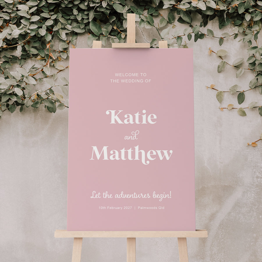 Modern pale pink wedding welcome sign with script font and Let the Adventures Begin heading