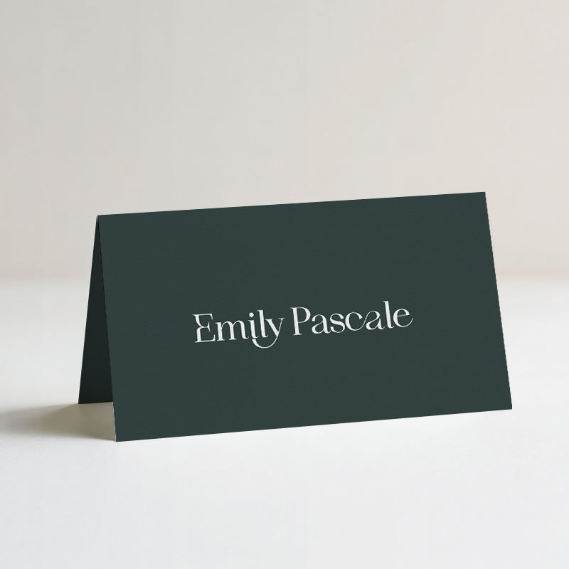 Modern emerald green folded wedding place card with display typography for guest names.