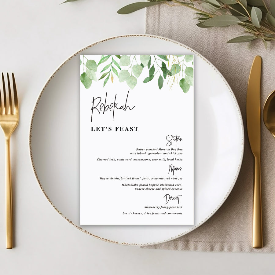 Wedding menu with greenery and eucalyptus leaves and modern font style with guest name printing.
