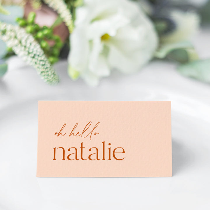Soft peach and orange folded wedding place cards tent style with oh hello before the guest name
