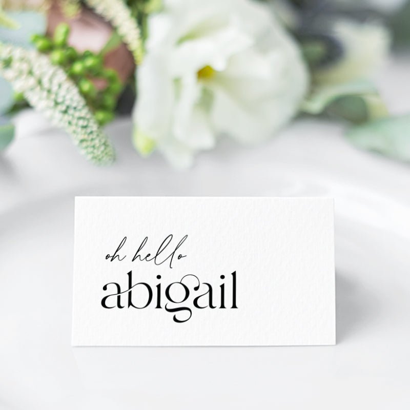 Black and white folded wedding place cards tent style with oh hello before the guest name