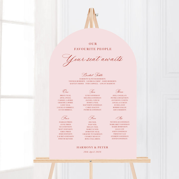 Wedding seating chart arch shape with traditional formal calligraphy in pink and terracotta red.