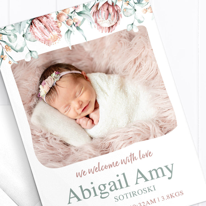 Baby girl birth announcement card with photo of baby and australian native flowers and greenery border, double sided