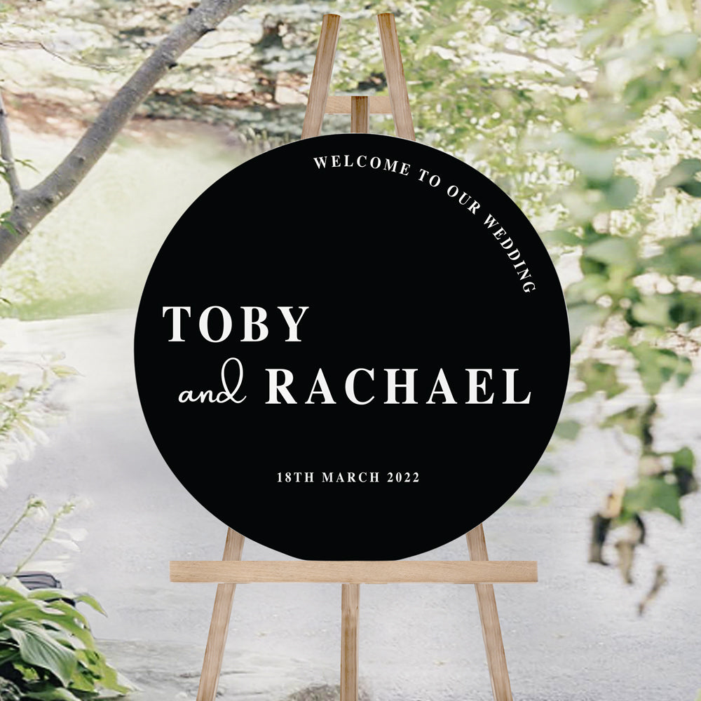 Modern bold wedding welcome sign in round shape, printed on black foamboard with white ink. Welcome to our wedding heading.
