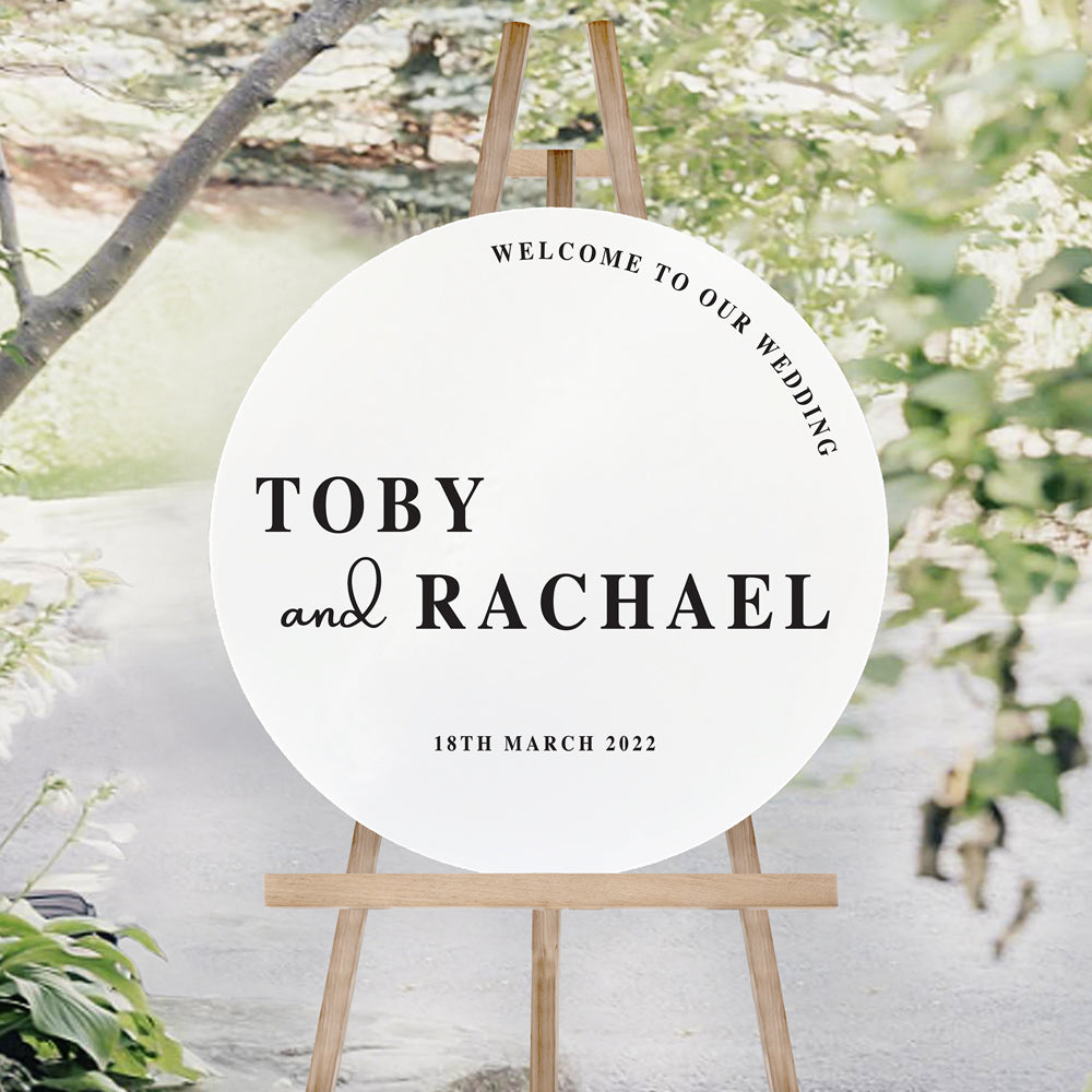 Modern bold wedding welcome sign in round shape, printed on white foamboard with black text. Welcome to our wedding heading.