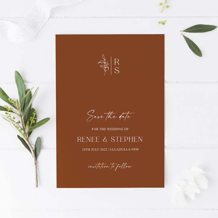 Minimal wedding save the date card with monogram at the top and hand drawn leaf, calligraphy on harvest or terracotta cardstock. Peach Perfect Australia