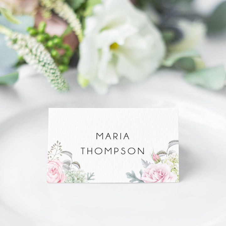 Folded wedding place card with calligraphy and pink flowers and greenery in both corners