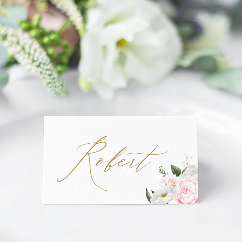 Wedding place cards with soft pink and apricot flowers and greenery, and beautiful calligraphy font in gold