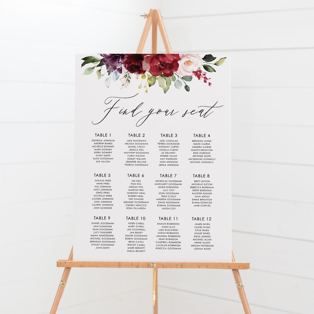 Wedding seating chart with striking red, burgundy and pink florals and foliage