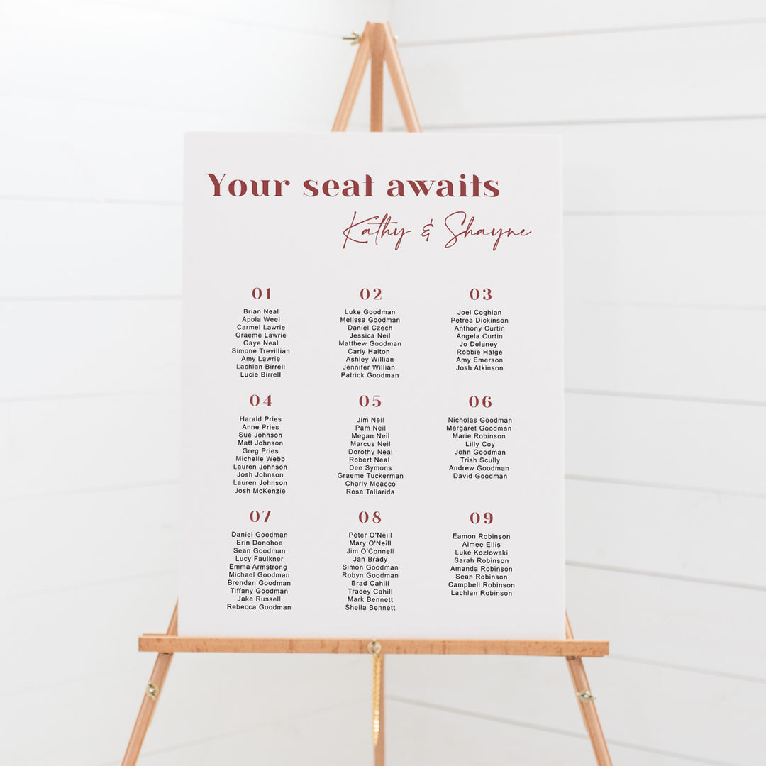 Modern wedding seating chart with Your Seat Awaits heading and calligraphy font for names. Terracotta and white text. Mounted to foam board or print your own budget design.