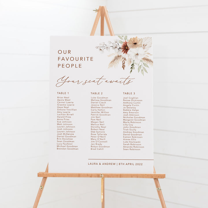 Bohemian wedding seating chart with calligraphy font and watercolour boho flowers, pampas grass and foliage, printed on foamboard for sitting on an easel.