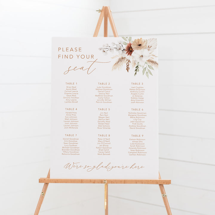 Bohemian wedding seating chart with calligraphy font and watercolour boho flowers, pampas grass and foliage, printed on foamboard for sitting on an easel.
