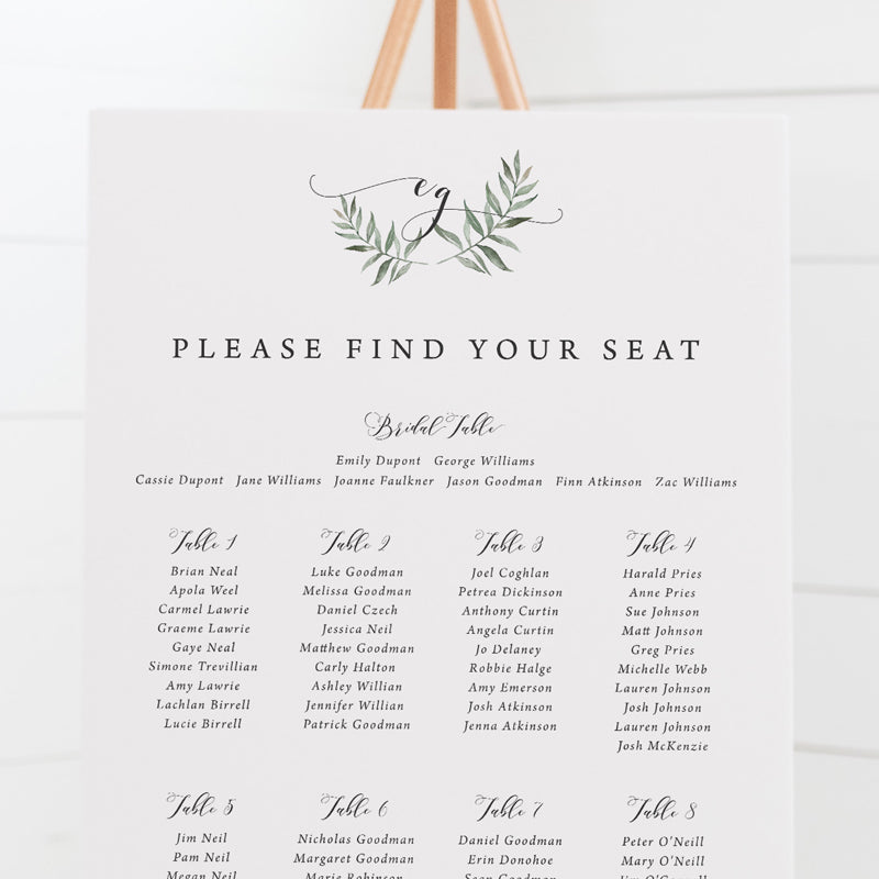 Wedding seating chart with monogram of bride and grooms initials in calligraphy and leafy wreath.