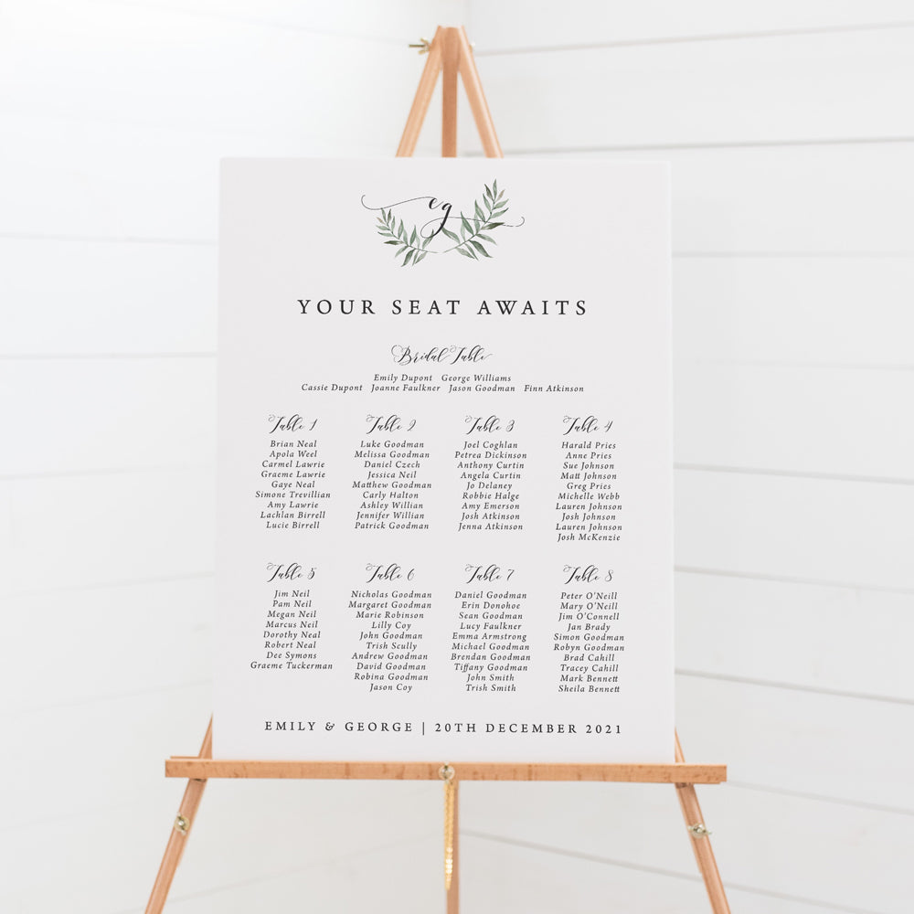 Wedding seating chart with monogram of bride and grooms initials in calligraphy and leafy wreath.
