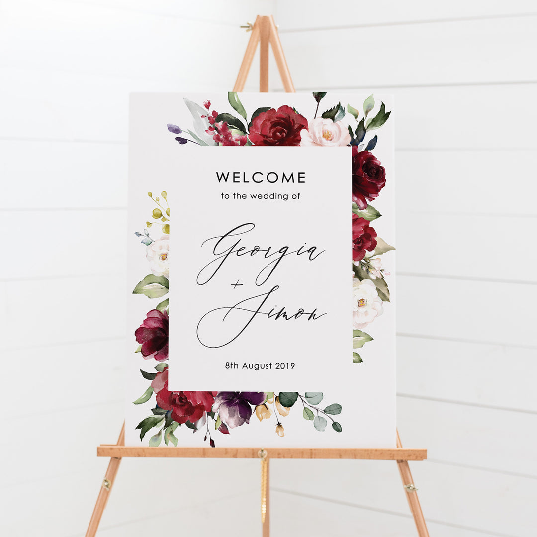 Wedding welcome sign with a border of deep red flowers and green foliage and beautiful calligraphy font, printed on card or foamboard