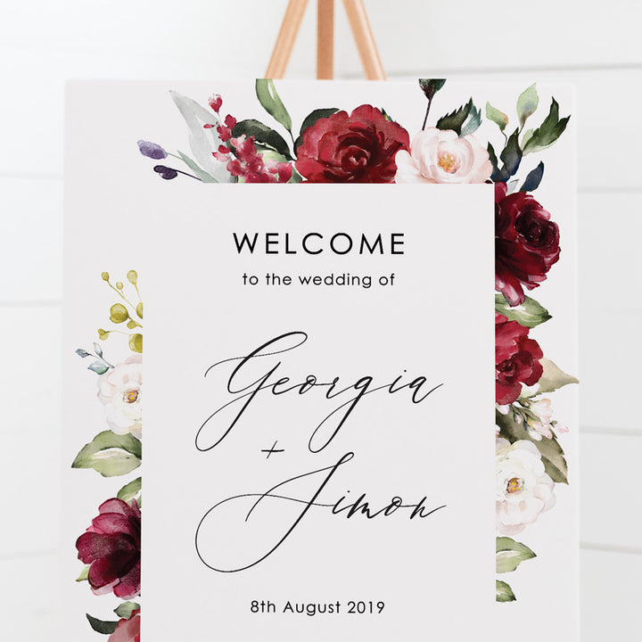 Wedding welcome sign with a border of deep red flowers and green foliage and beautiful calligraphy font, printed on card or foamboard