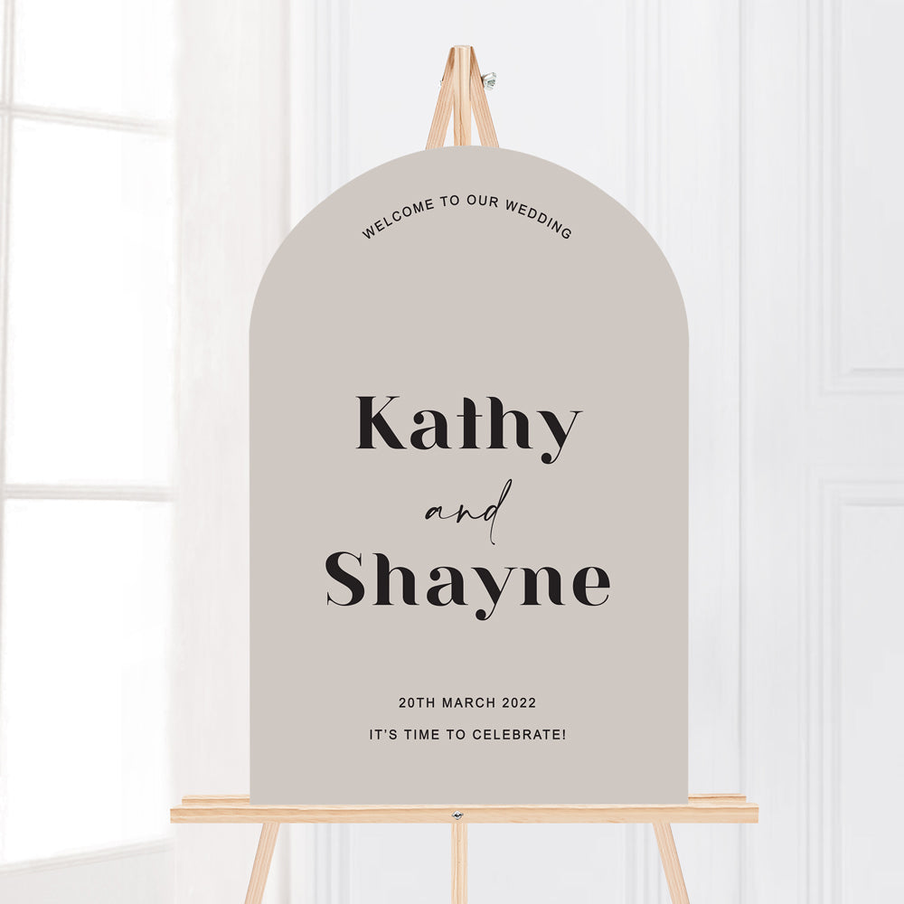 Modern wedding welcome sign in arch shape on easel. Trendy fonts. Stone coloured wedding sign black text.